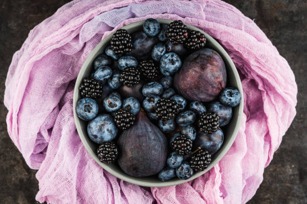 Dark berries and fruits in the bowl on the rustic background. Shot from above. Selective focus.