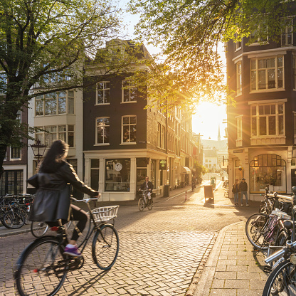 Amsterdam, Netherlands - September 22, 2021: The girl rides a bike. Early morning in Amsterdam. Sunny quiet street of an ancient European city. Amsterdam, Holland, Netherlands, Europe