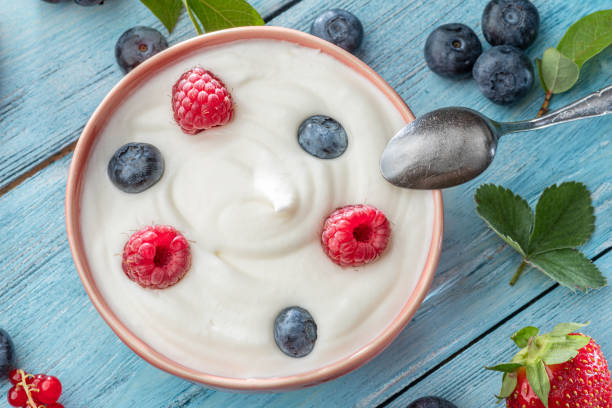 istock Ceramic bowl with plain yoghurt and berries on the table. Light summer mood. 1345936748