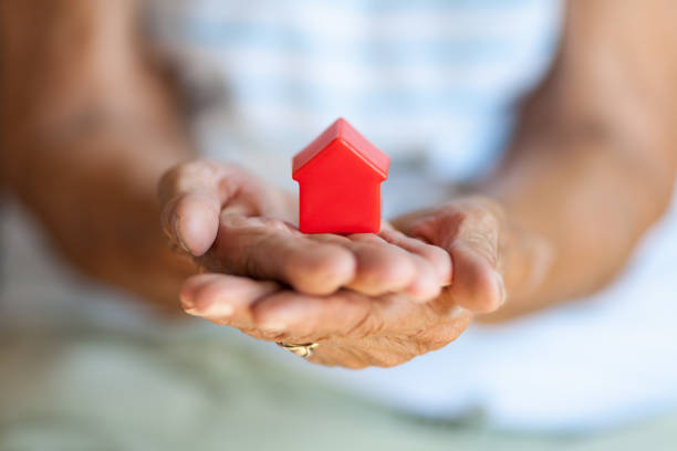 Elderly woman and her property Elderly woman holding a small house in her hands gift lounge stock pictures, royalty-free photos & images