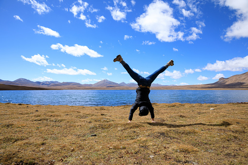 Woman doing handstand on high altitude grassland under blue sky