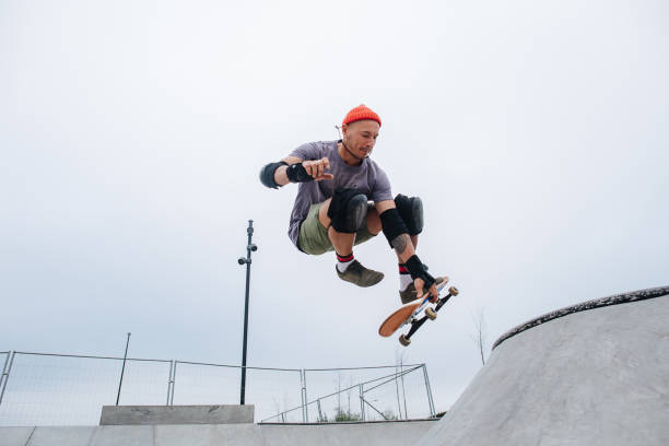 istock Impressive mature skater in watch cap starting his roll, jumping with his board 1345938562