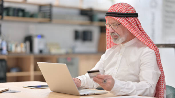 istock Old Arab Businessman Shopping Online 1345939665