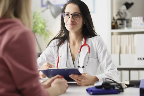 happy smiling woman doctor is receiving patient at clinic - outpatient imagens e fotografias de stock