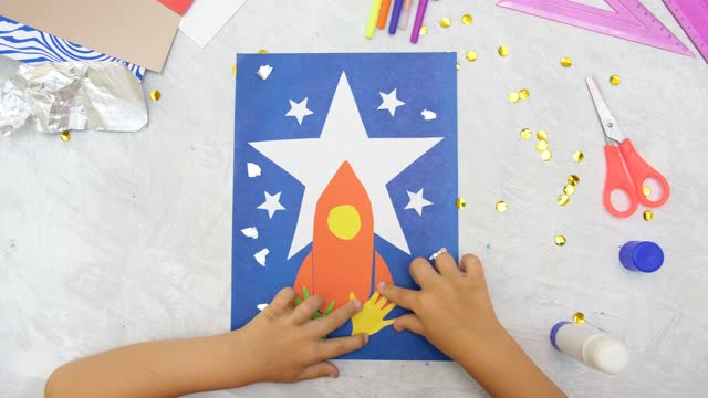Child making rocket and stars from paper. Creative children play with craft. The space theme development of children.  School education handmade creativity.