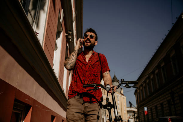 istock Urban man using a phone and pushing a bike 1345941355