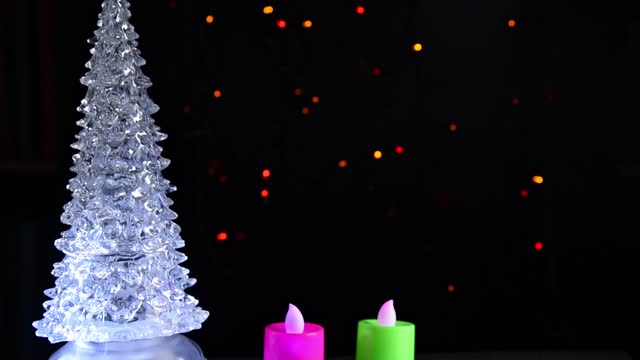 Christmas tree and candles on black shimmering background, bokeh