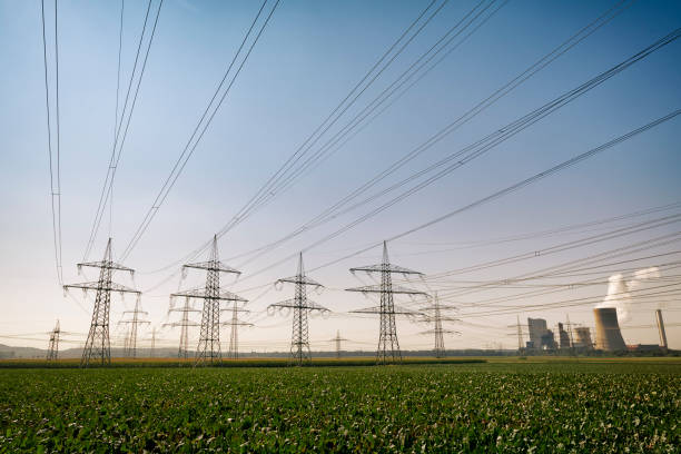 Brown-coal burning power plant with pollution beside a group of electricity pylons, Germany.