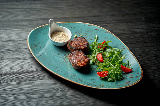 istock Grilled beef medallions with salad and white sauce. 1345945899