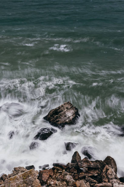 Sea wave crashing on rock coast with dark clouds