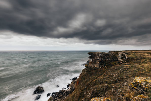 Sea wave crashing on rock coast with dark clouds