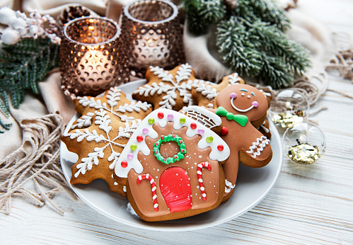 Christmas gingerbread in the plate and candles on white wooden background. Top view.
