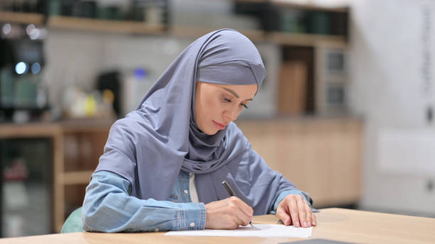 istock Arab Woman Writing on Paper at Work 1345948479