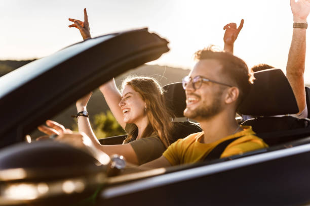 istock Young happy people going on a road trip by convertible car. 1345950071