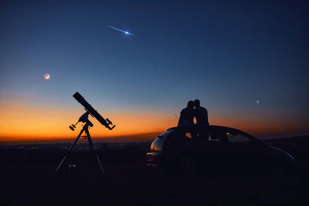 istock Couple stargazing together with a astronomical telescope. 1345950388