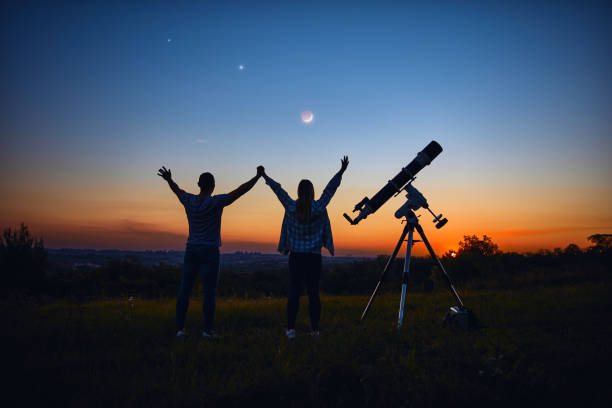 istock Couple stargazing together with a astronomical telescope. 1345950431