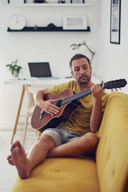 istock Man playing acoustic guitar at home. 1345950479