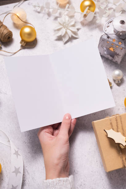 istock Woman's hands holding blank card on white background. Chritsmas winter design. 1345953776