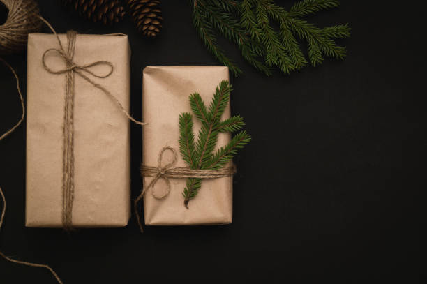 istock Creative DIY hobby. Making a modern handmade Christmas and New Year gift on a black background. Boxes of craft paper, jute twine, fir branches, present decorations. Top view, DIY concept, copy space 1345953859