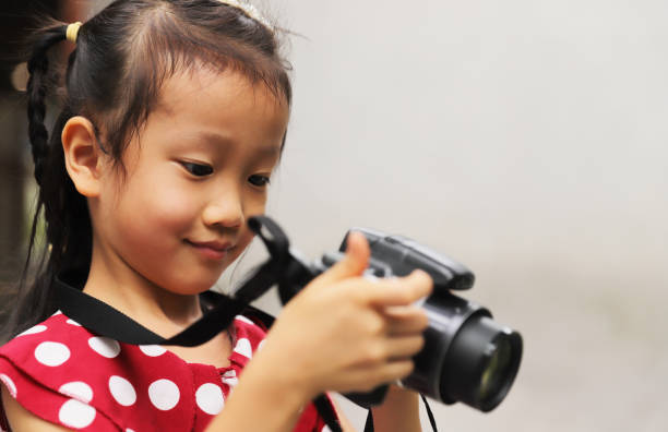 istock a Asian girl take photos with a digital camera. 1345953987