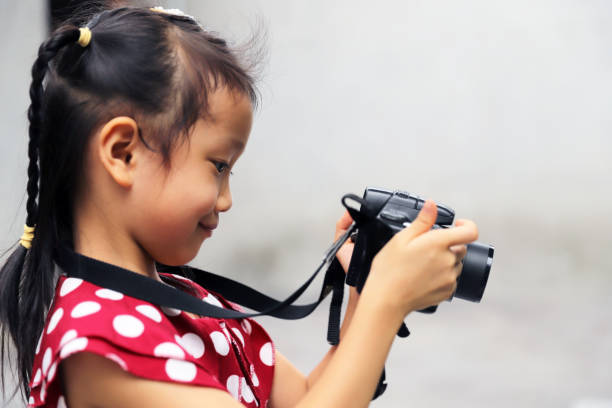 istock a Asian girl take photos with a digital camera. 1345954031