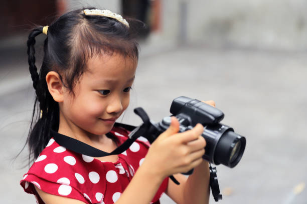 istock a Asian girl take photos with a digital camera. 1345954598