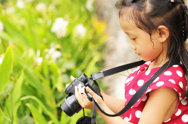 istock a Asian girl take photos with a digital camera. 1345954660