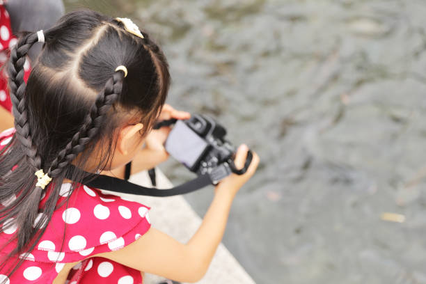 istock a Asian girl take photos with a digital camera. 1345954689