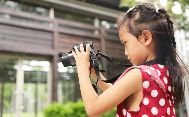 istock a Asian girl take photos with a digital camera. 1345954733