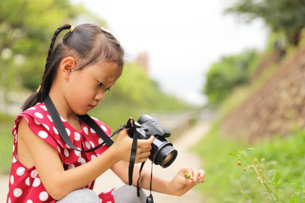istock a Asian girl take photos with a digital camera. 1345954850