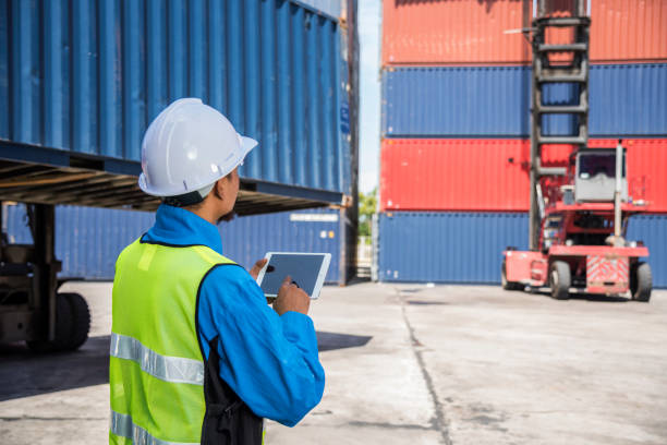 istock Foreperson with digital tablet working in port shipping containers 1345954977
