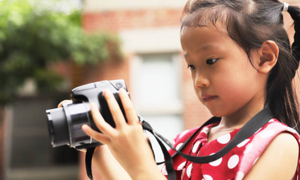 istock a Asian girl take photos with a digital camera. 1345954992