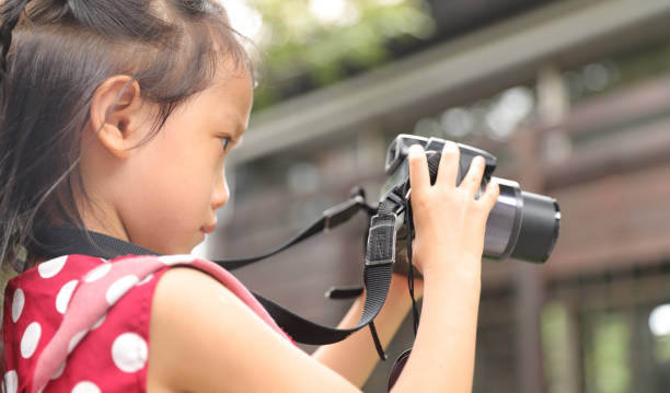 istock a Asian girl take photos with a digital camera. 1345955041