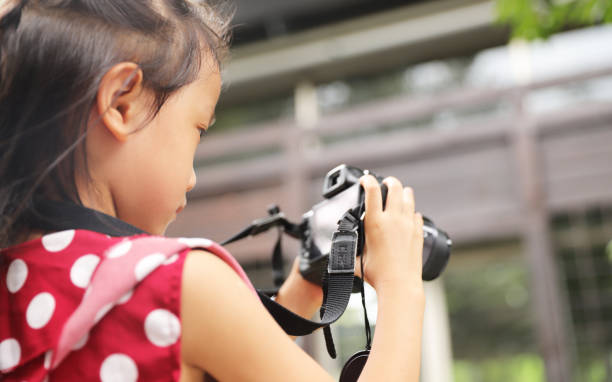 istock a Asian girl take photos with a digital camera. 1345955056