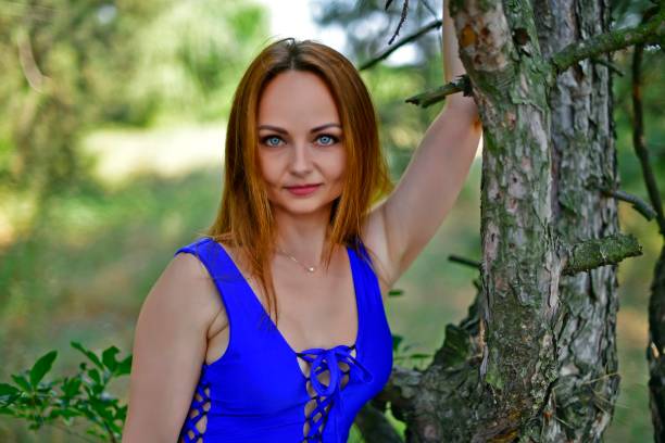 Beautiful young woman, in a blue swimsuit, on an unusual tree.