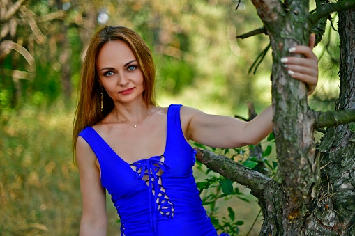 Beautiful young woman, in a blue swimsuit, on an unusual tree.