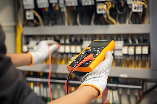 El ingeniero electricista utiliza un multímetro para probar la instalación eléctrica y la corriente de la línea eléctrica en un gabinete de control del sistema eléctrico. photo
