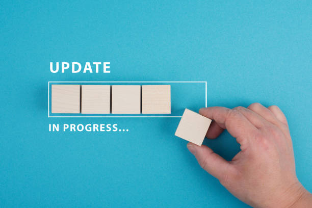 The words update in progress are standing beside the loading bar, hand puts last cube to the upload, blue colored background stock photo