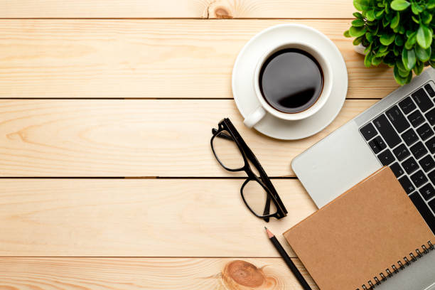 istock Top view office table desk. Workspace with blank, office supplies,Laptop, pencil, green leaf, and coffee cup on wood background. 1345962871