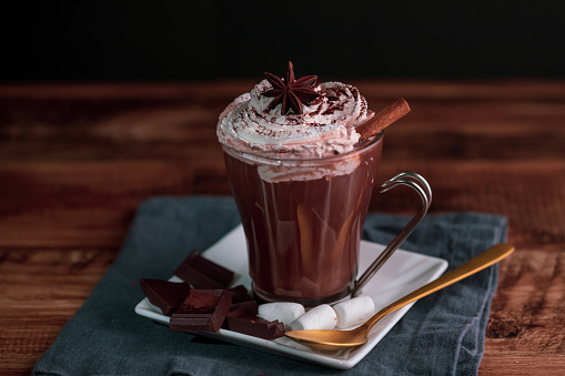 Hot Chocolate with whipped cream,cinnamon and star anise served on a wooden table