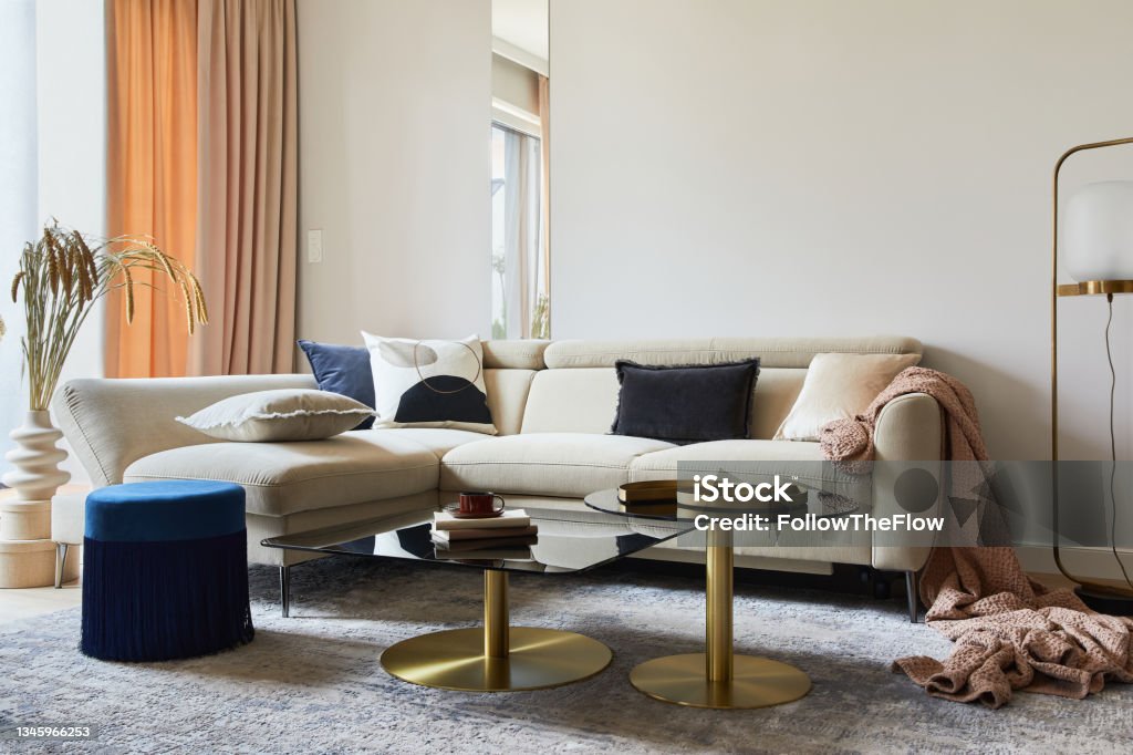 Glamorous living room interior design with modern beige sofa, glass coffee table, red armchair and golden accessories. Template. Glamour Stock Photo