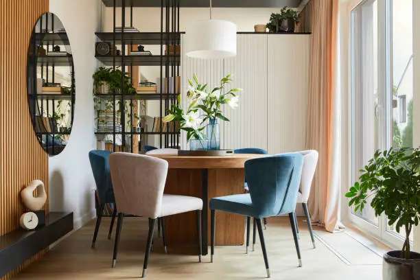 Photo of Stylish composition of elegant dining room interior design with velvet armchairs, design rounded wooden table and beautiful personal accessories. Glamour interior design inspiration. Template.
