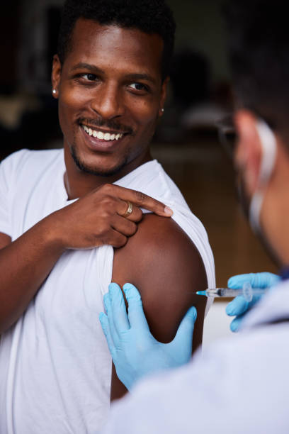 istock Smiling young man getting a vaccination shot from a doctor 1345967601