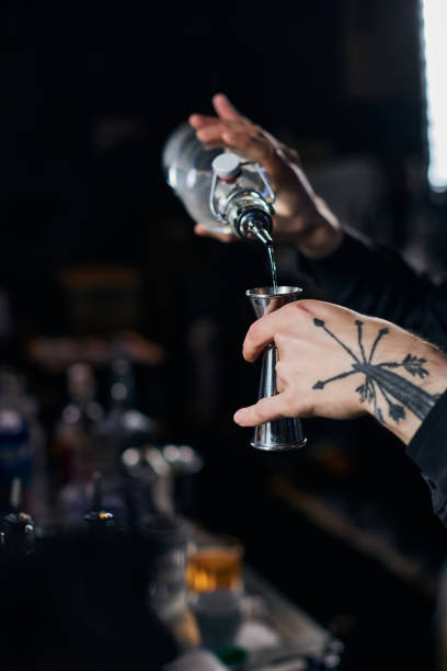 istock Bartender in apron adds ingredient to glass 1345968111
