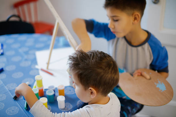 istock Two boys sitting at the table at home and painting for fun 1345968913
