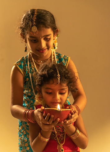 Beautiful two young Indian girl aged 6 and 4 years holding Diwali oil lamp