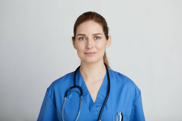 A female nurse looking at the camera. Front view of a woman in blue medical scrubs. female nurse photos stock pictures, royalty-free photos & images