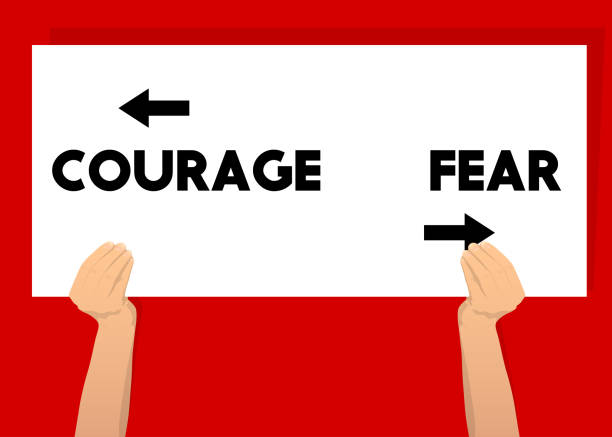 istock Hand holding banner with Courage and fear text with arrows on white paper. 1345974880