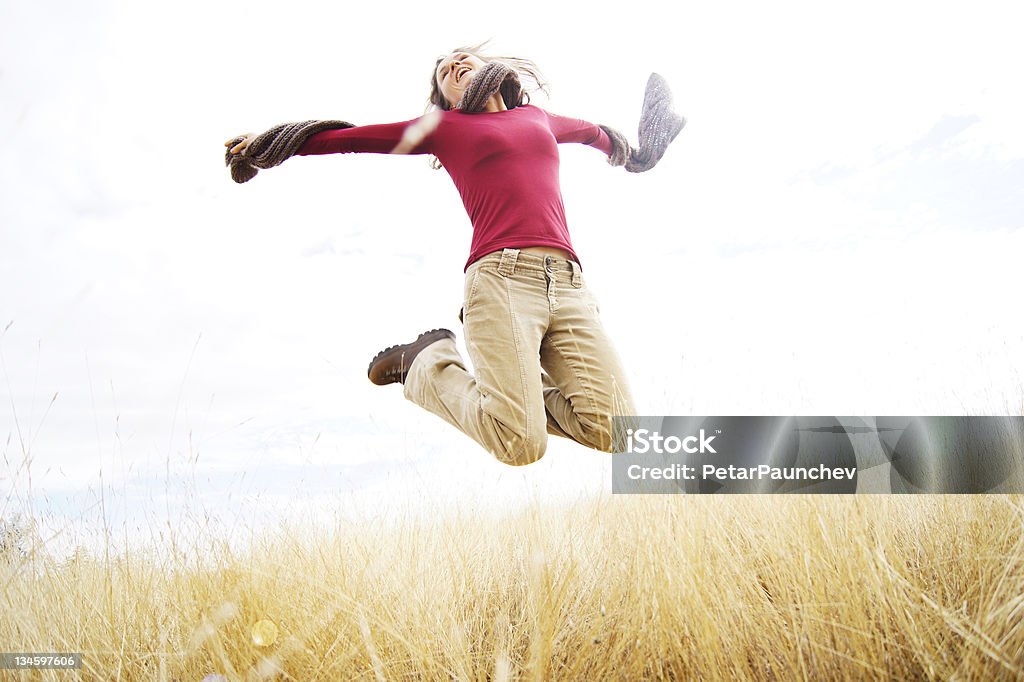 Freedom Beautiful young girl jumping with joy in a long grass field Activity Stock Photo