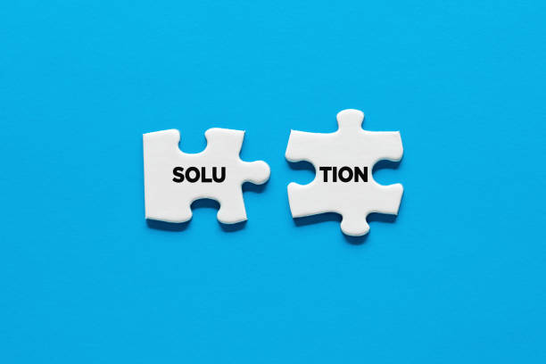istock Two puzzle pieces are connecting the word solution. Synergy, teamwork, unity or solidarity 1345976138